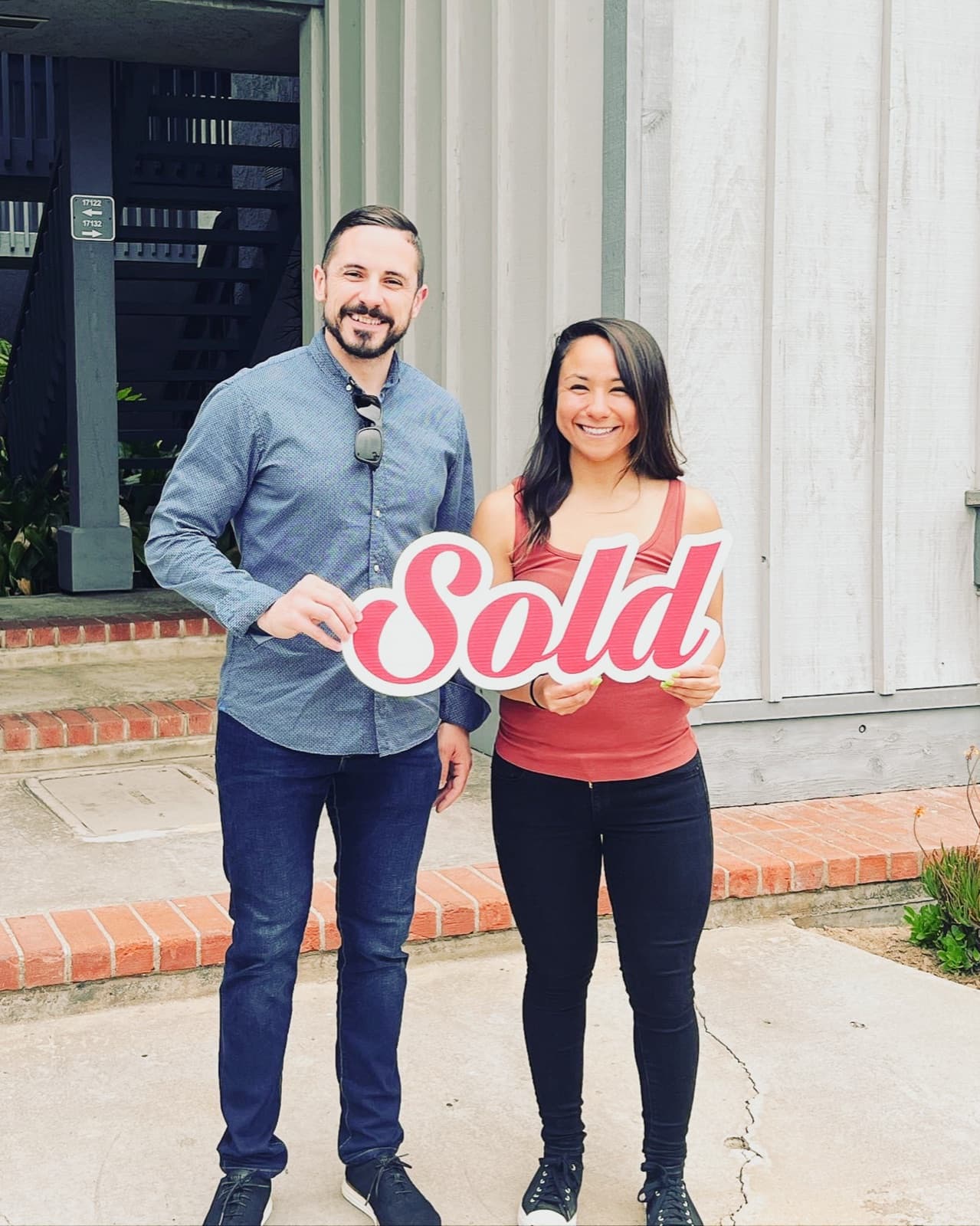 Ortiz Group buyers on closing day holding a Sold sign outside their new home