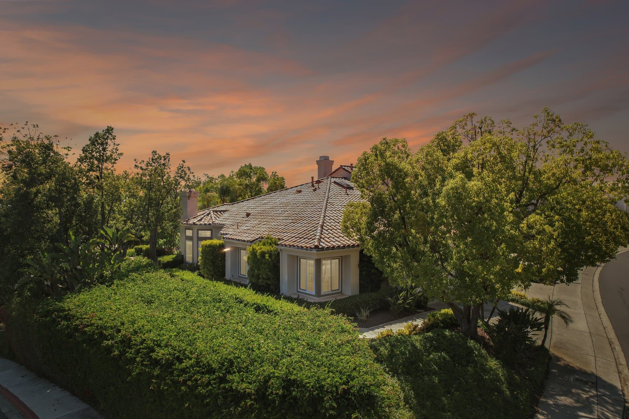 Aerial of a large foothill estate at twilight, home set into the canyon terrain